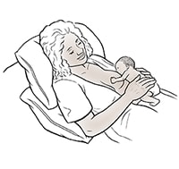 Female breastfeeding premature baby in laid-back position.