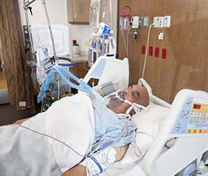 Intubated person in intensive care unit bed.